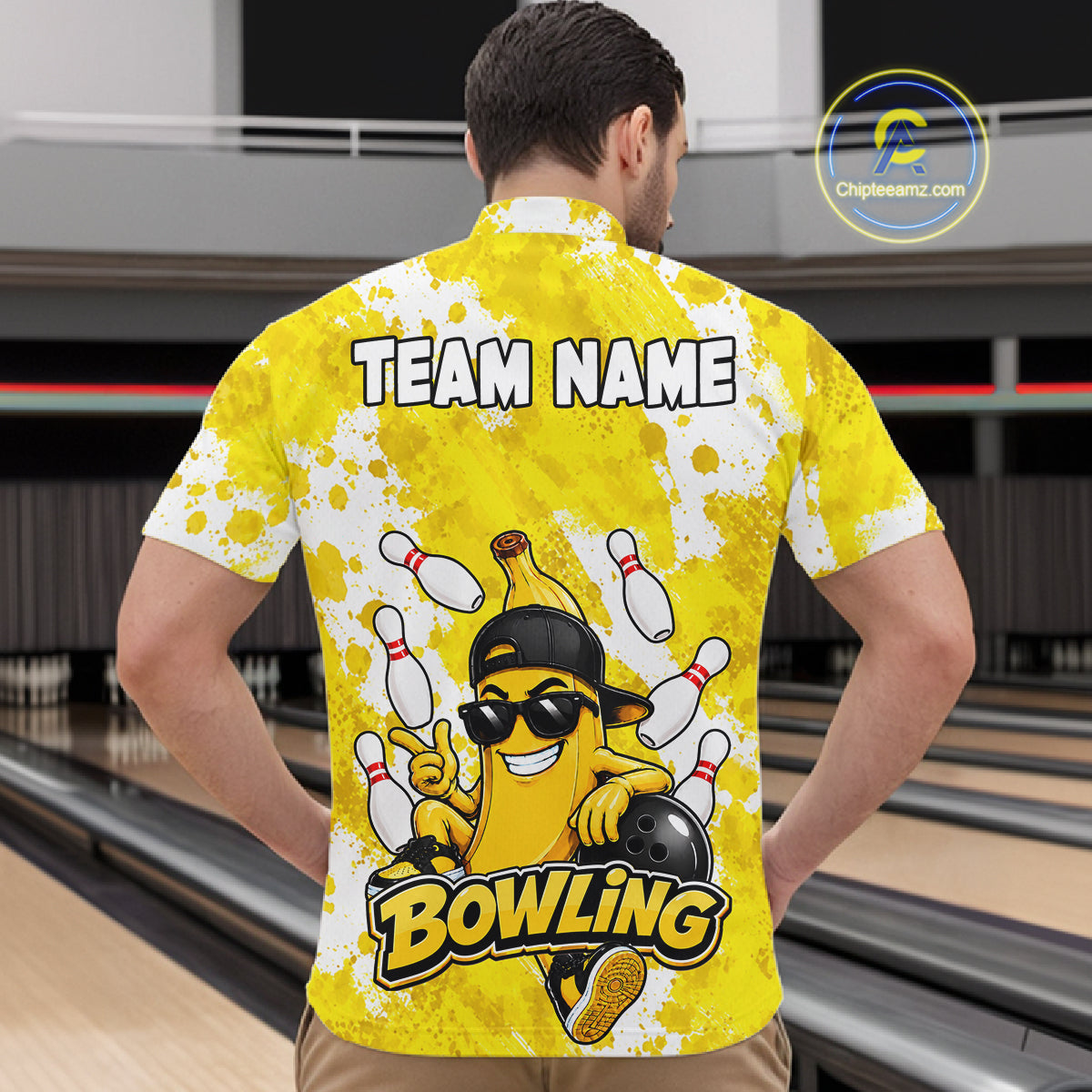 Back view of man wearing a funny yellow banana bowling quarter zip shirt in a bowling alley.