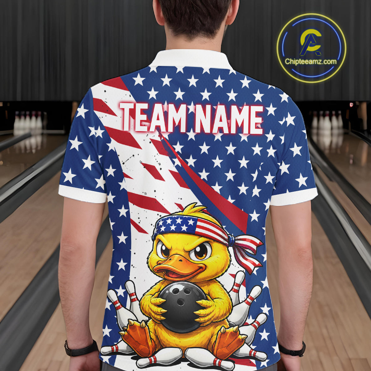 Person wearing a bowling shirt with a duck holding a bowling ball design and American flag, in a bowling alley.