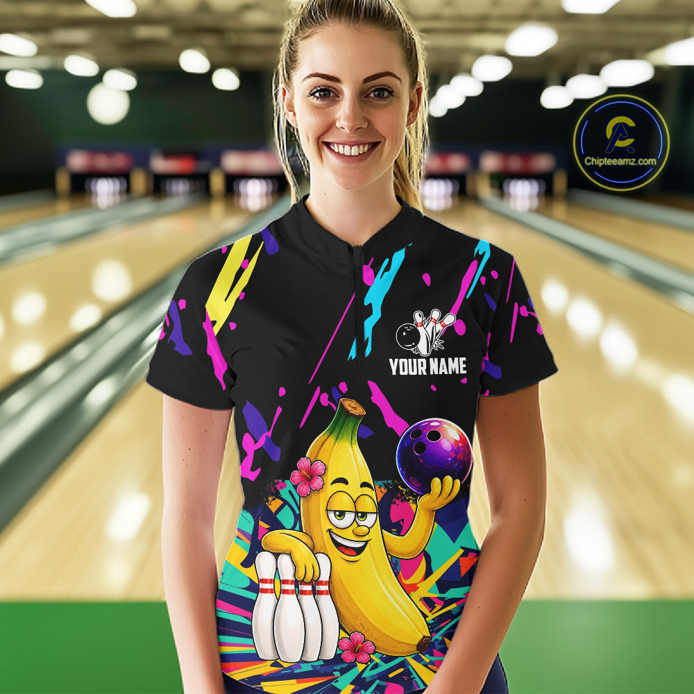 Woman wearing a colorful bowling shirt with a cartoon banana character in a bowling alley.
