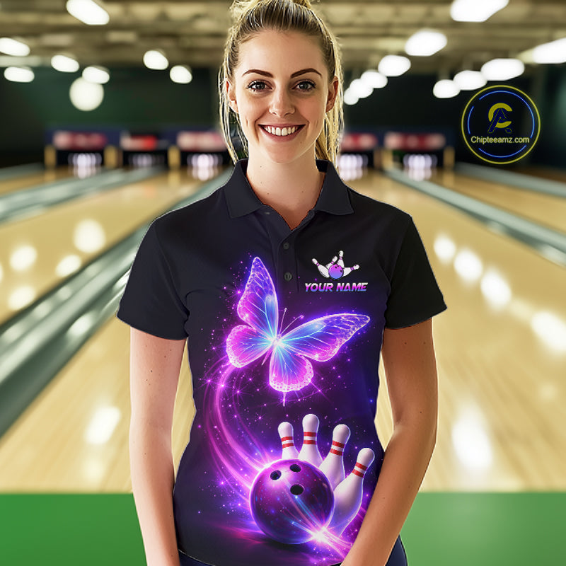 Woman wearing a black bowling shirt with a colorful butterfly design in a bowling alley.
